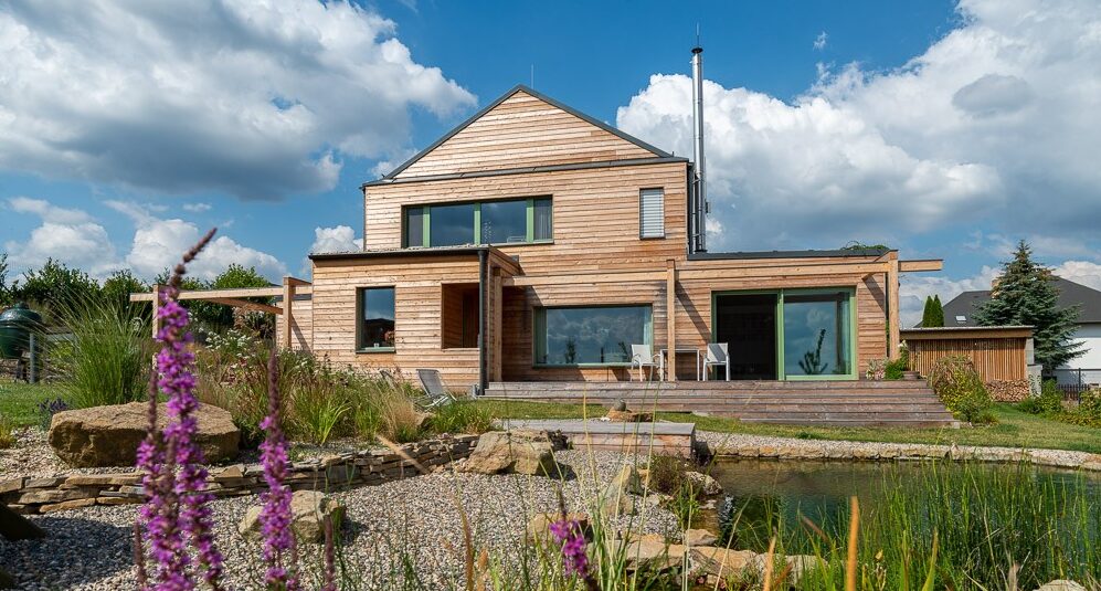 Ilustrační fotografie rodinného domu 3AE z CLT panelů s dřevěnou fasádou a jezírkem