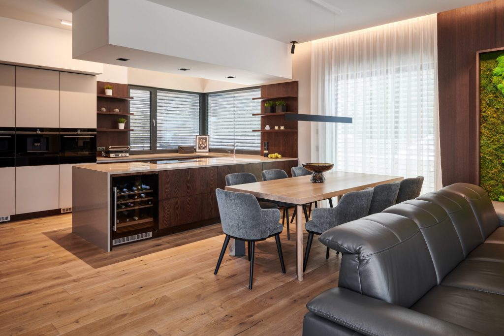 Kuchyň s ostrůvkem, jídelním stolem a vestavěnou vinotékou v moderní dřevostavbě