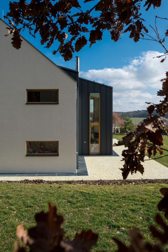 Vstupní část domu s vysokým oknem a kombinovanou fasádou