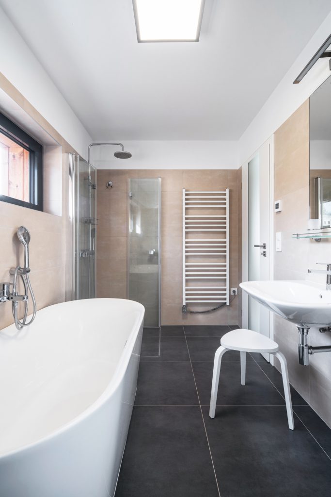 Koupelna s volně stojící vanou, sprchovým koutem bez vaničky a otopným žebříkem