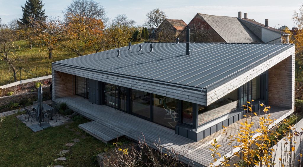 Dřevostavba firmy 3AE s rovnou střechou, dřevěnou fasádou a terasou v zahradě