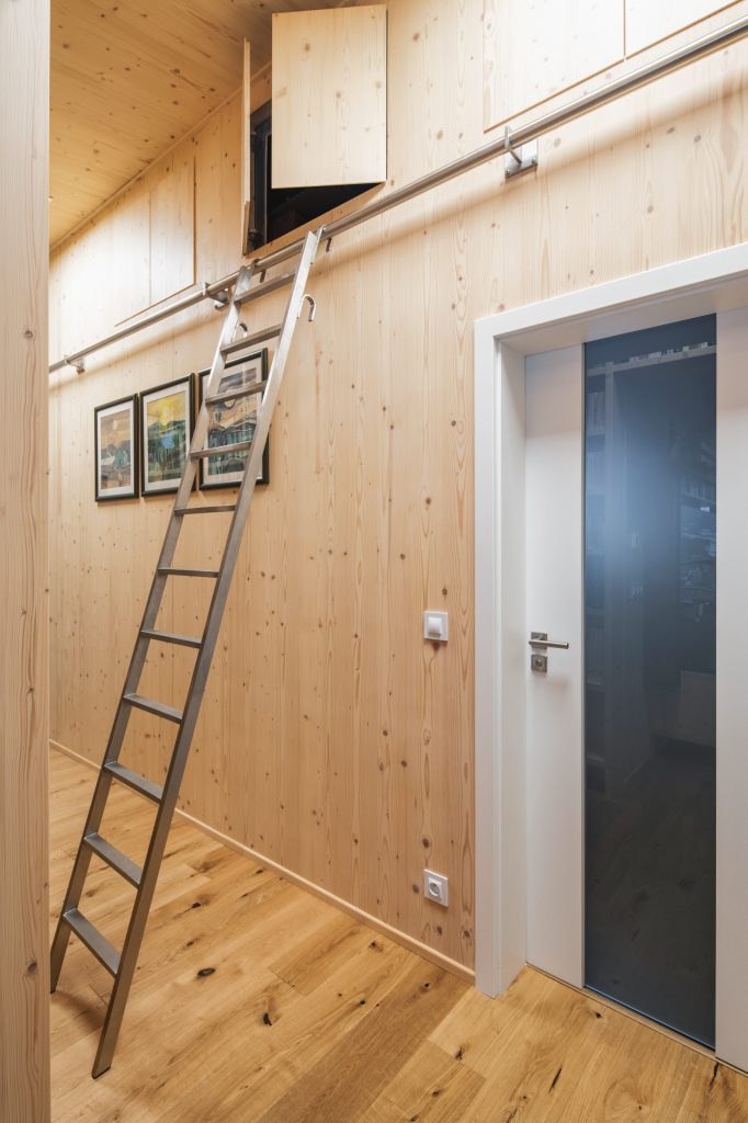 Dřevěná stěna z CLT panelů s horním úložným prostorem a žebříkem