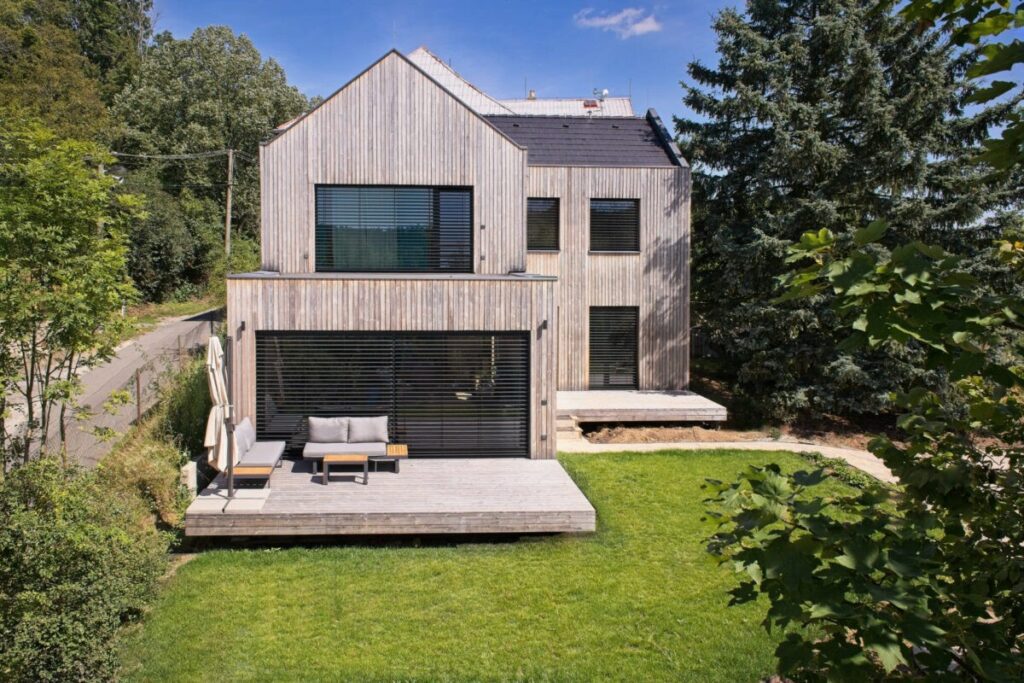 Dům s dřevěnou fasádou, sedlovou střechou a velkou terasou v zahradě