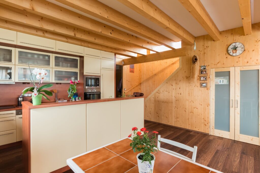 Kuchyně a jídelní kout s dřevěnými trámy a masivními panely Novatop