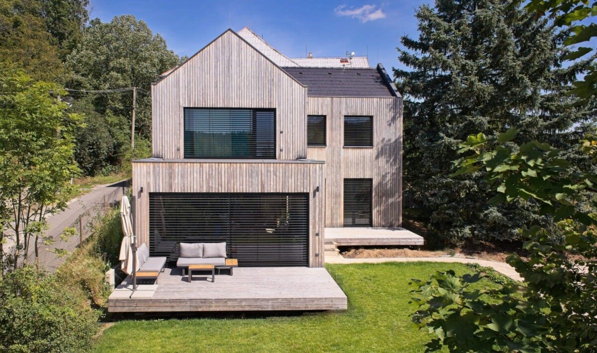 Moderní rodinný dům s dřevěnou fasádou, sedlovou střechou a velkou terasou v zahradě