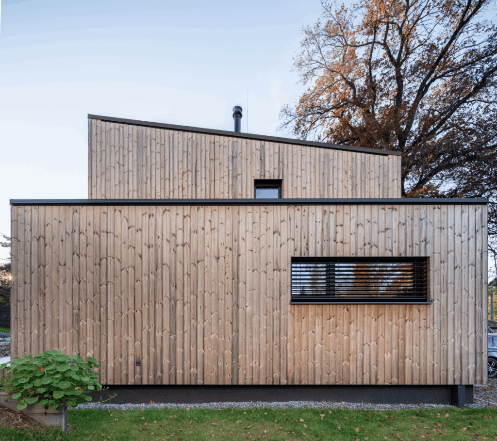 Dům s dřevěnou fasádou a okny na jižní straně, orientovaný do zahrady