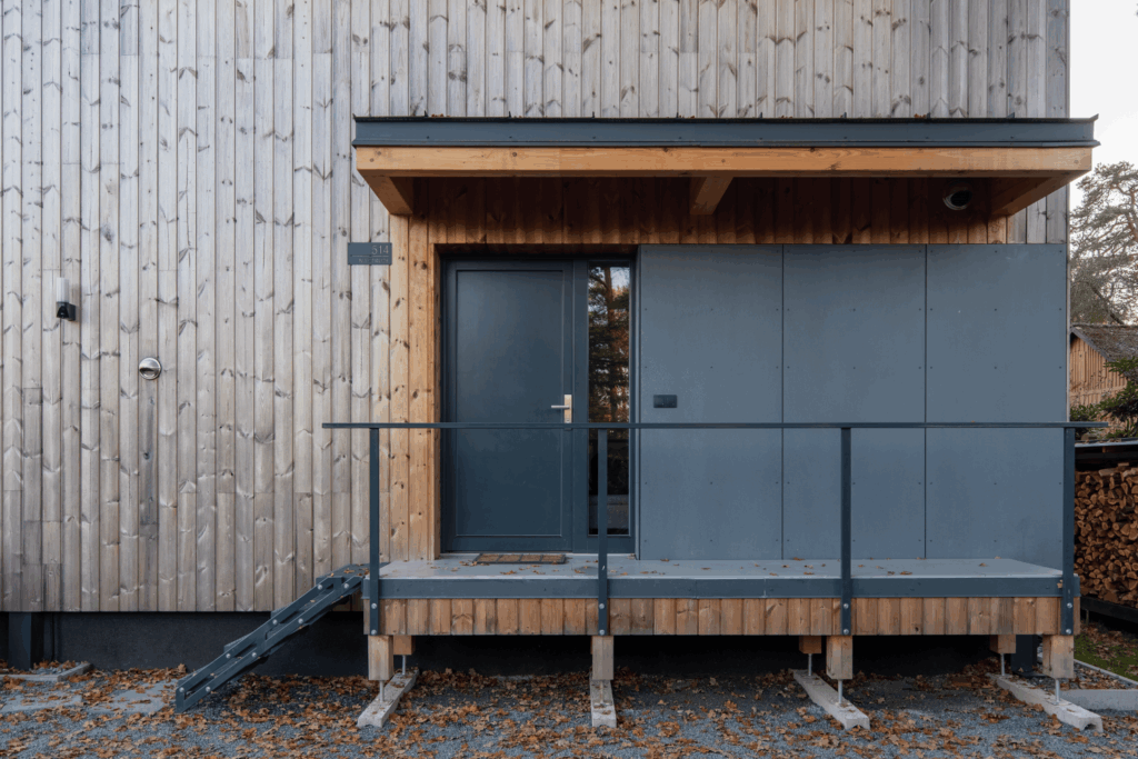 Vstupní dveře a terasa s dřevěnou fasádou a minimalistickým zábradlím