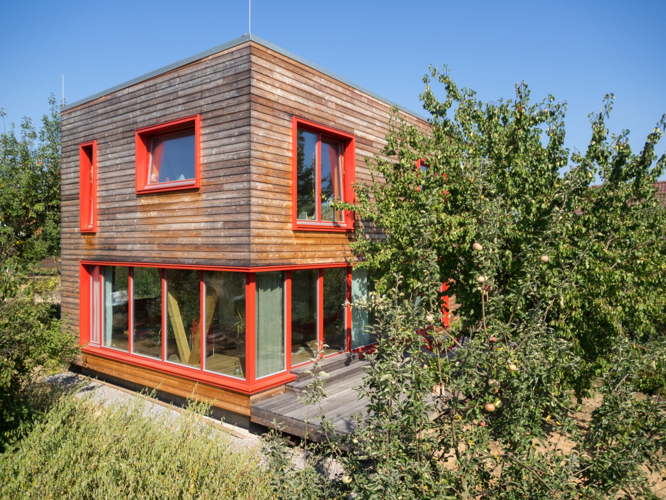 Moderní dvoupodlažní dřevostavba 3AE s dřevěnou fasádou a červenými okny
