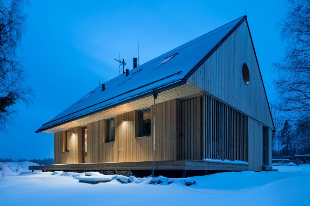 Čelní fasáda dřevostavby s osvětlením a sněhem