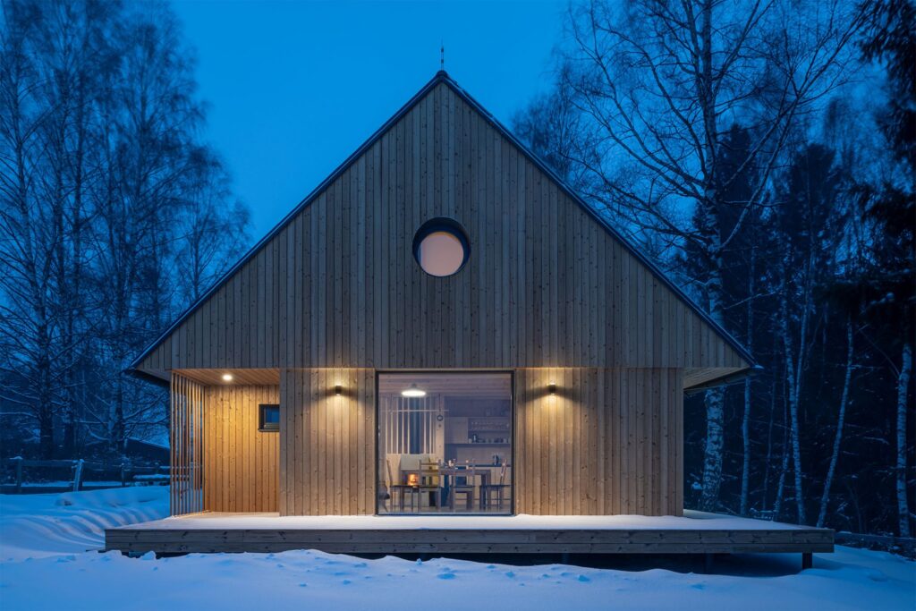 Večerní dřevostavba se světlem v zasněžené krajině