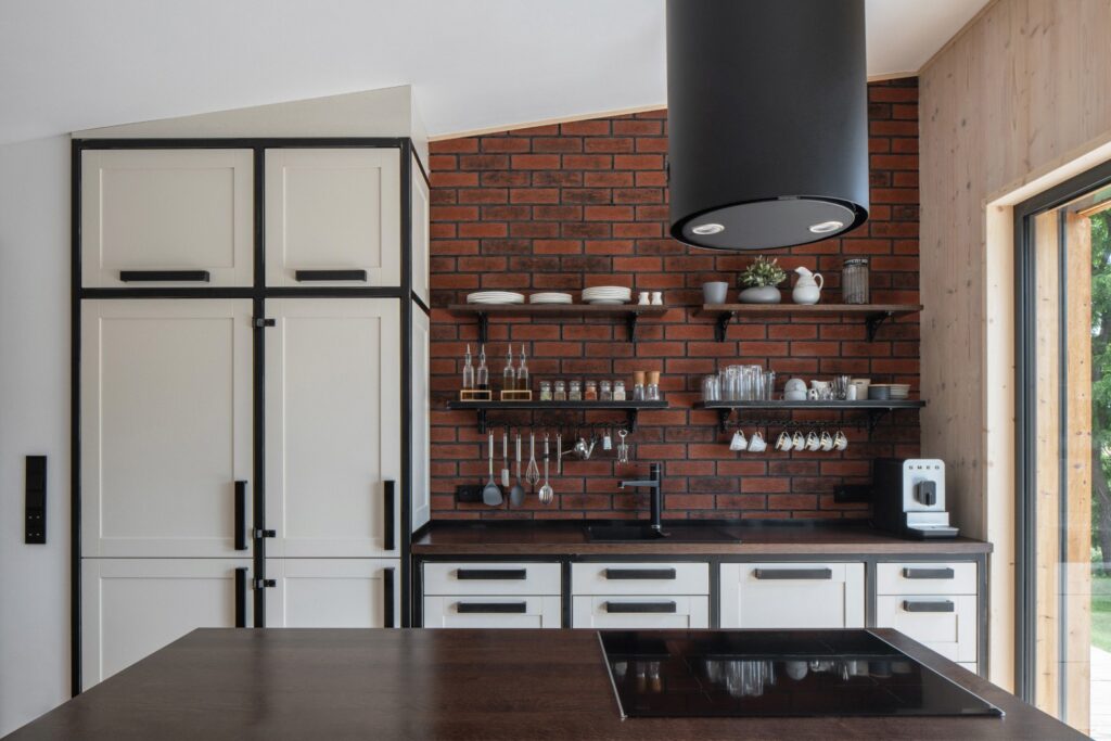 Detail kuchyňské linky s cihlovým obkladem a černou digestoří
