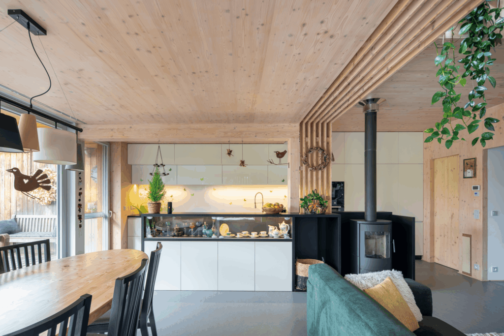 Interiér s dřevěným stropem, kuchyňskou linkou, krbem a jídelním stolem