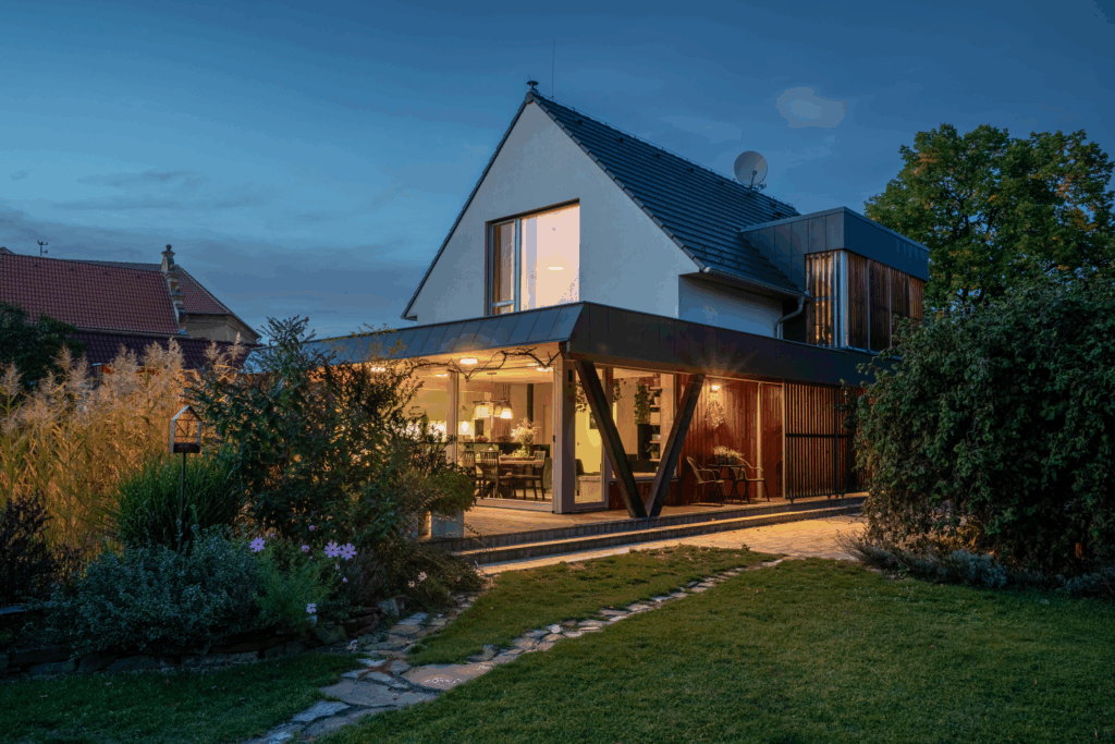 Rodinný dům s krytou terasou, sedlovou střechou a velkými prosklenými plochami směrem do zahrady