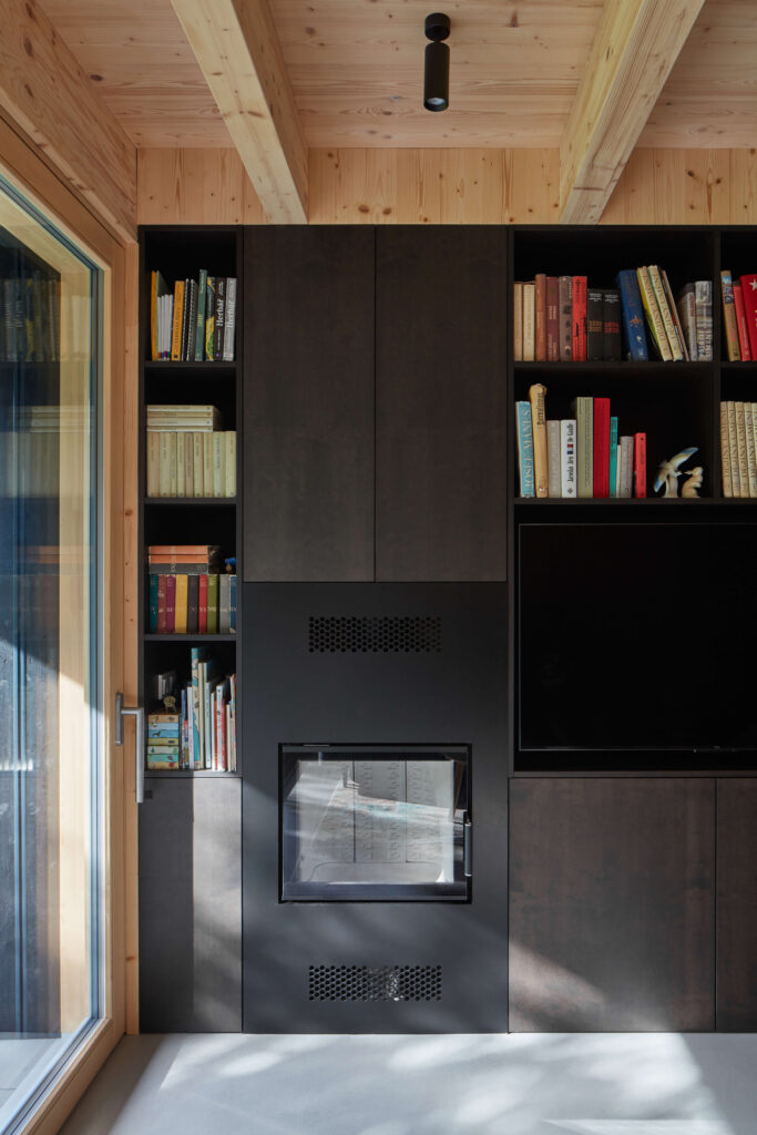 Obývací pokoj se stěnou knihovny a vestavěným krbem, dřevěné povrchy.
