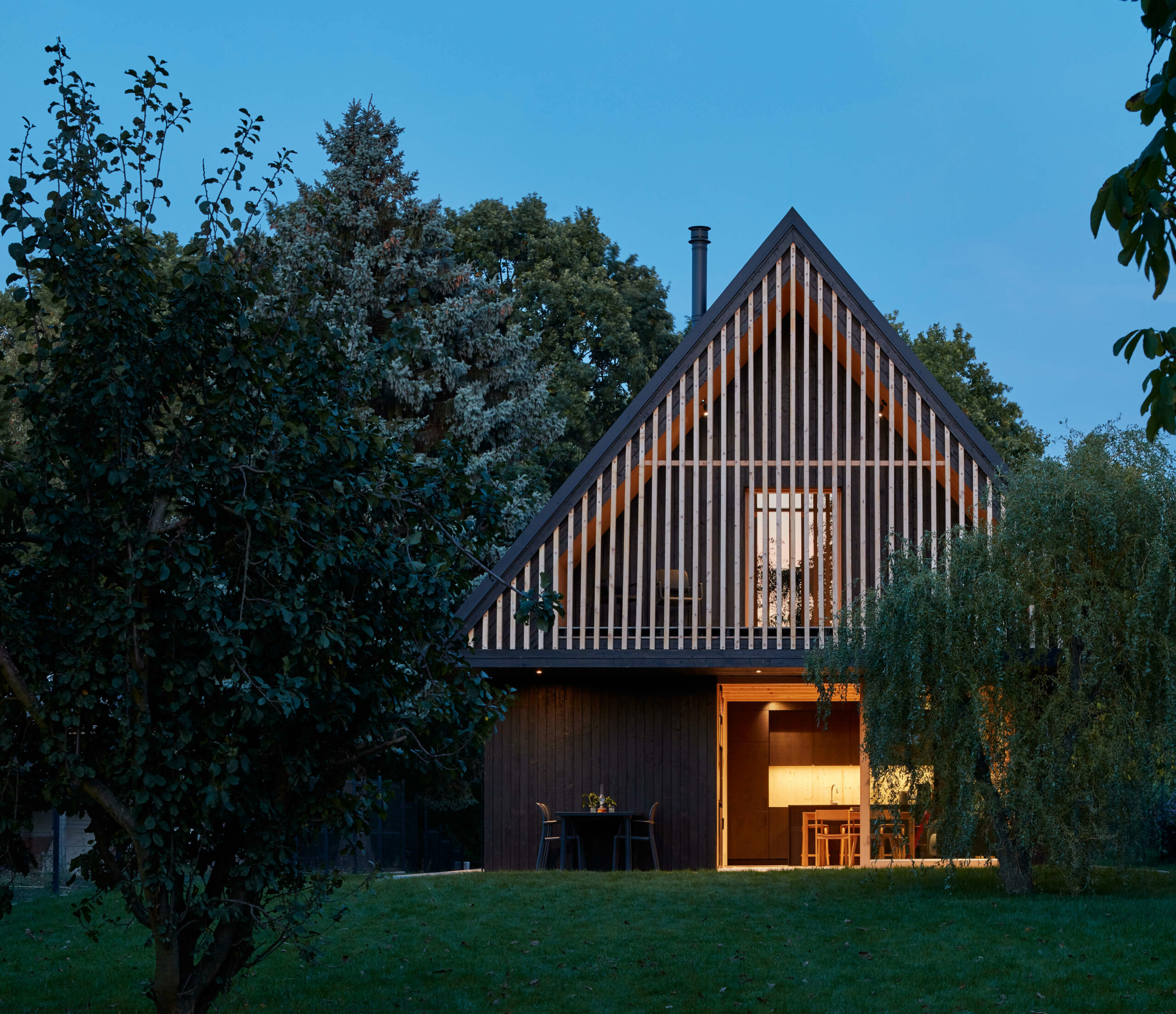 Rodinný dům s dřevěnou fasádou a vertikálními lamelami.