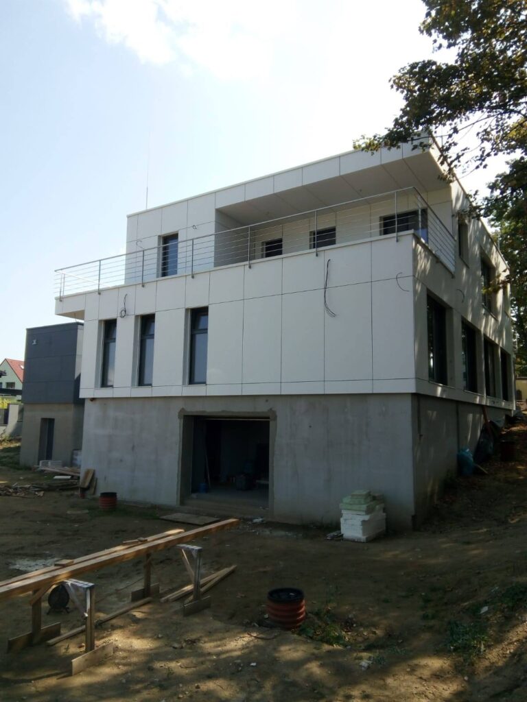 Třípodlažní komerční dřevostavba z CLT panelů s bílou fasádou a betonovým základem