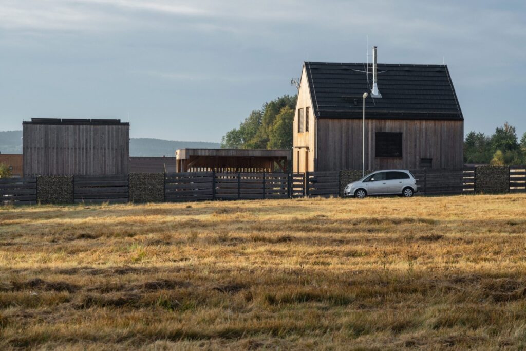Typový dům s přístavbami, dřevěným oplocením a příjezdovou cestou v horské krajině
