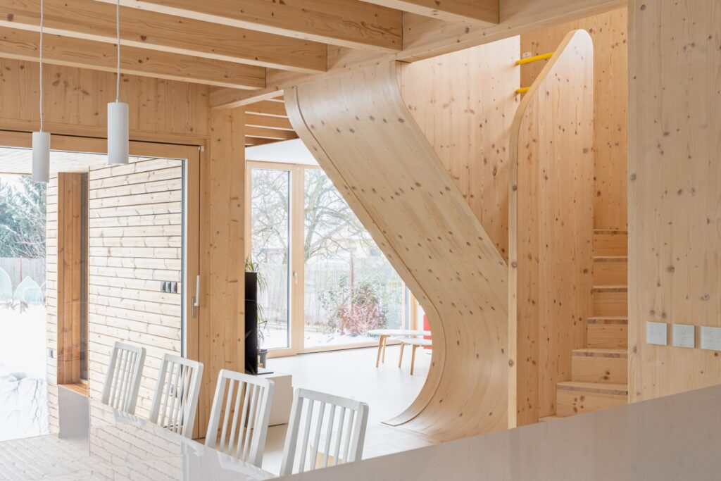 Interiér s jídelnou a zakřiveným dřevěným schodištěm z CLT panelů
