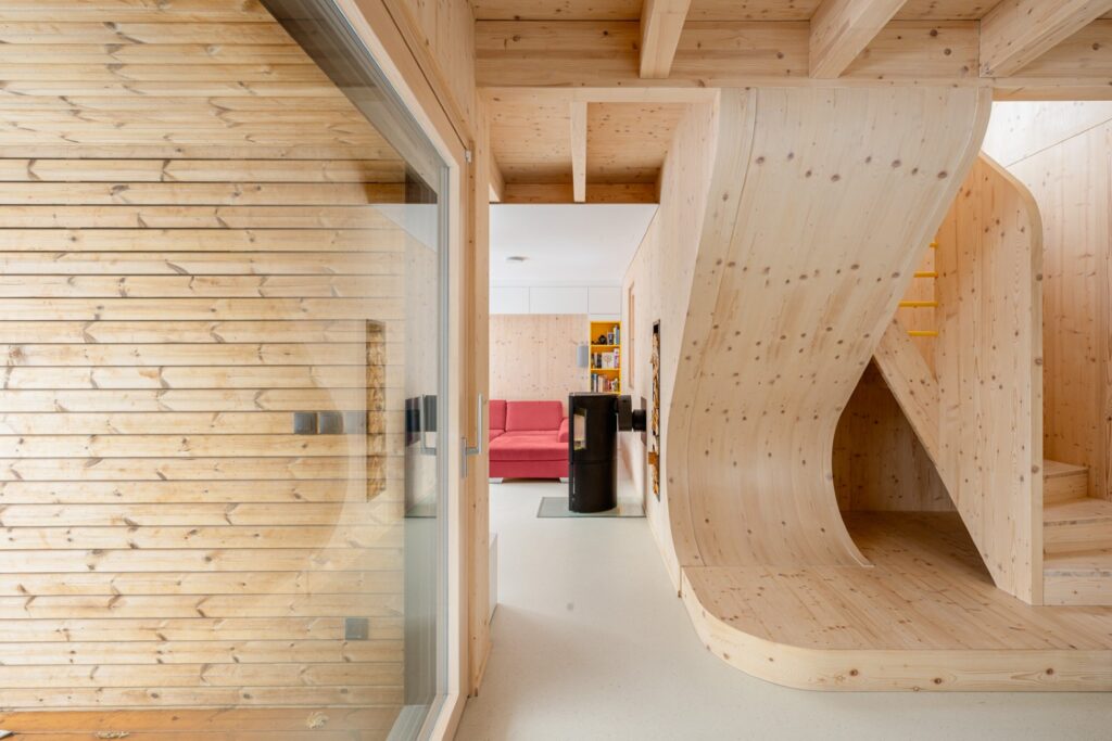 Interiér s vlnovitým schodištěm z CLT panelů a pohledem do obývací části