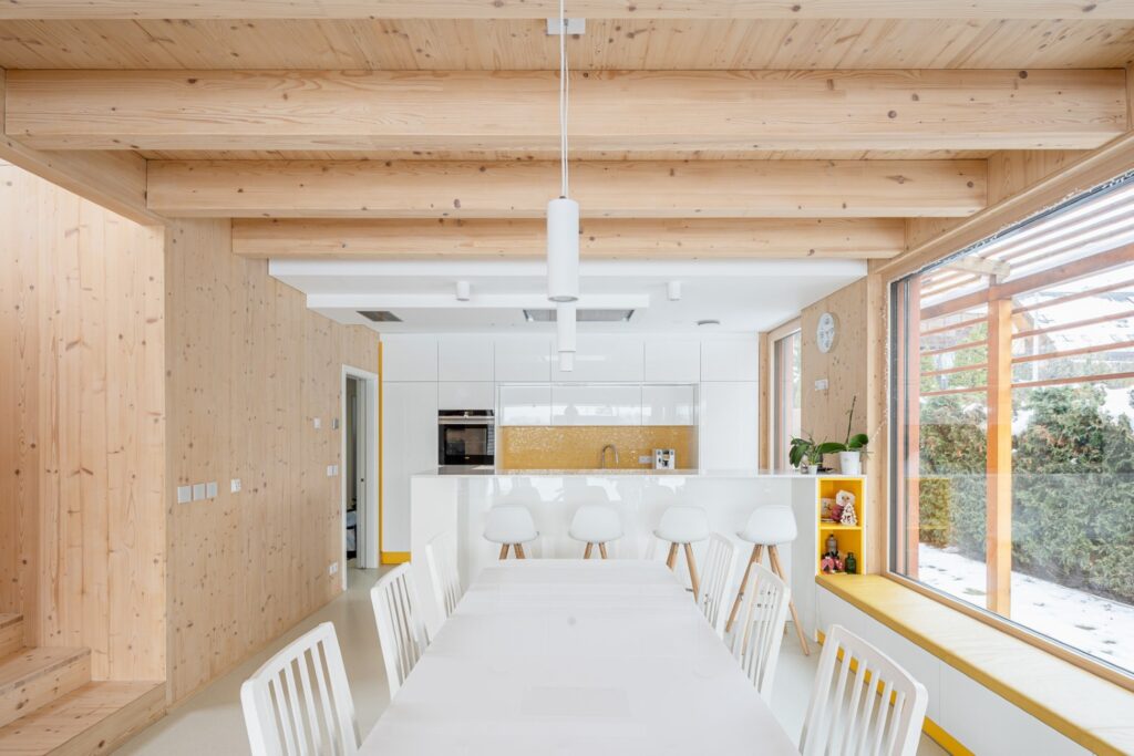 Jídelna a kuchyně v moderní dřevostavbě s CLT interiérem a velkým oknem