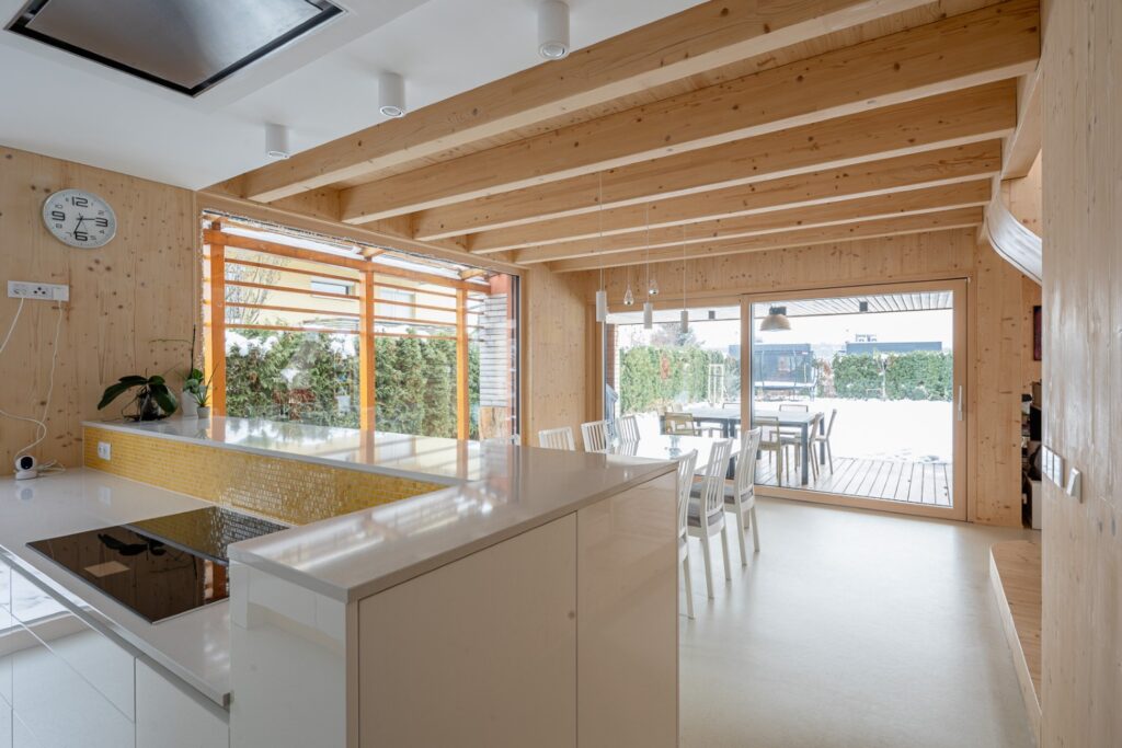 Kuchyně a jídelna v interiéru dřevostavby s CLT panely a výhledem na terasu
