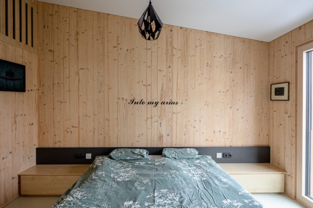 Ložnice s manželskou postelí a stěnami z masivních CLT panelů