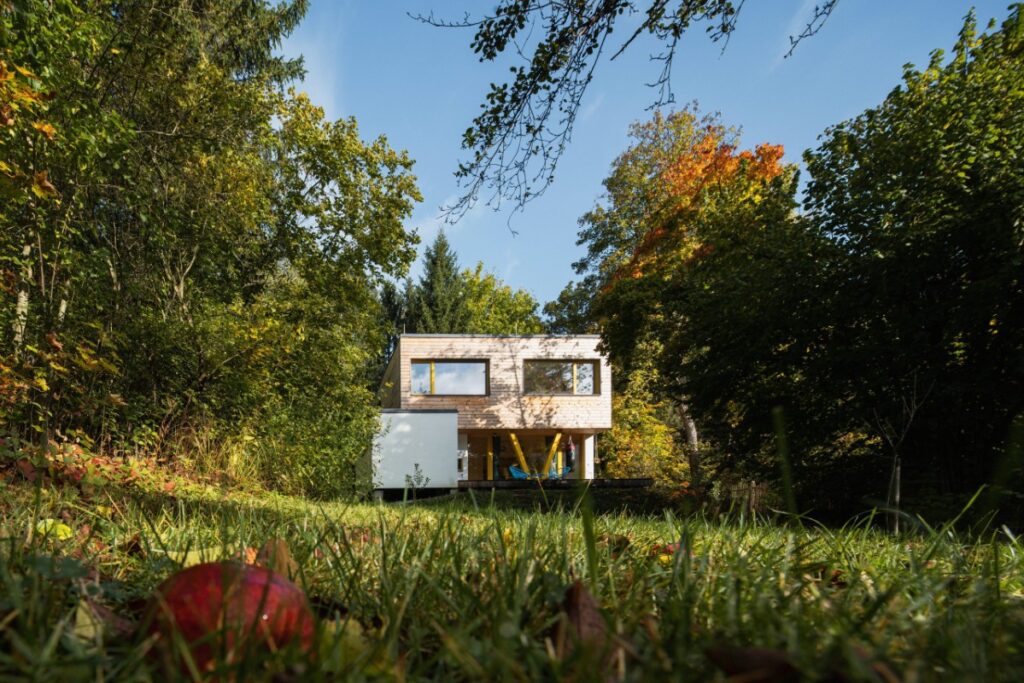 Minimalistický dvoupodlažní dům z CLT panelů obklopený stromy