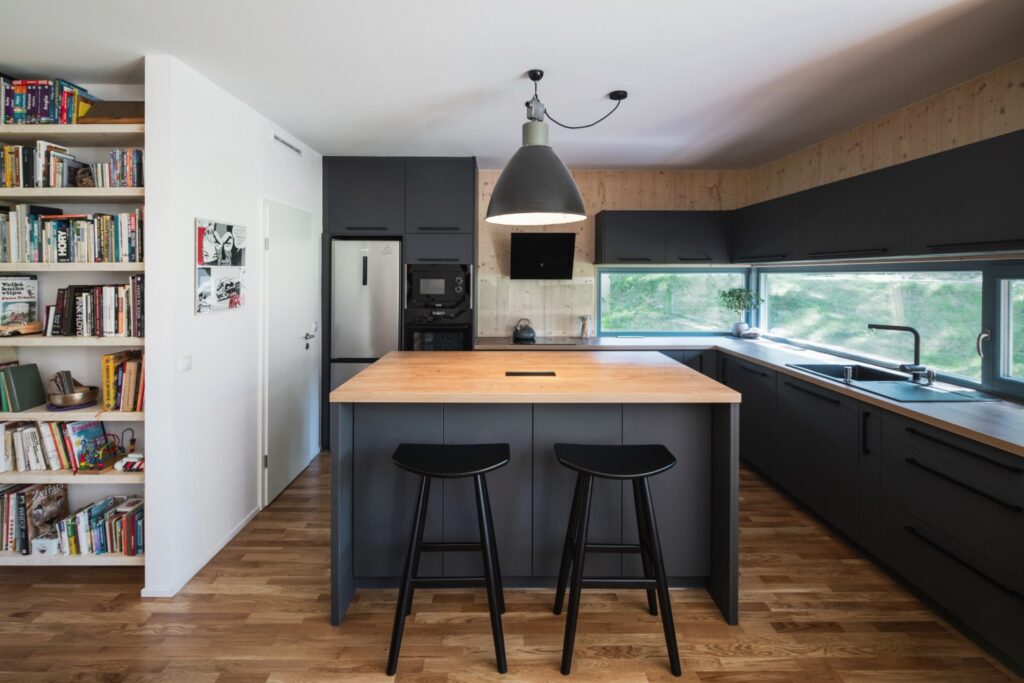 Kuchyňský ostrůvek a černá kuchyňská linka s výhledem přes široké okno