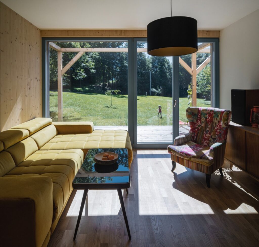 Obývací pokoj s velkými posuvnými dveřmi a výhledem na zahradu