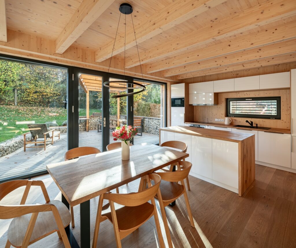 Obývací pokoj s kuchyní, dřevěným stropem a výhledem do zahrady