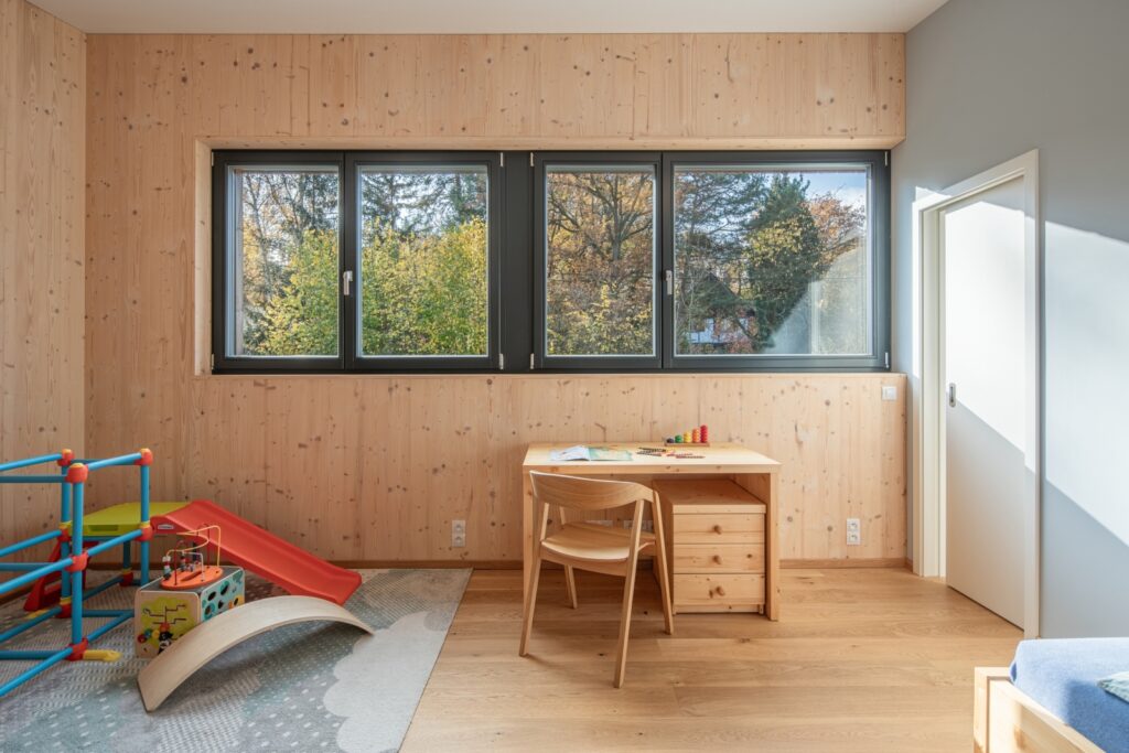 Dětský pokoj s dřevěnými stěnami a výhledem na zahradu
