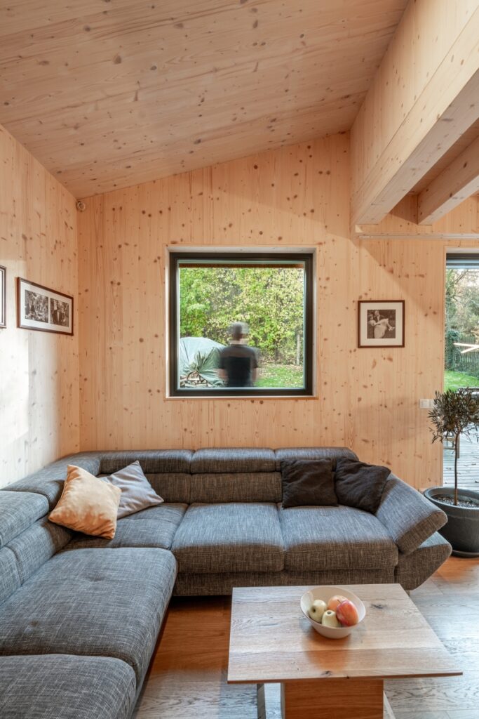 Obývací pokoj s dřevěnými stěnami a výhledem do zahrady