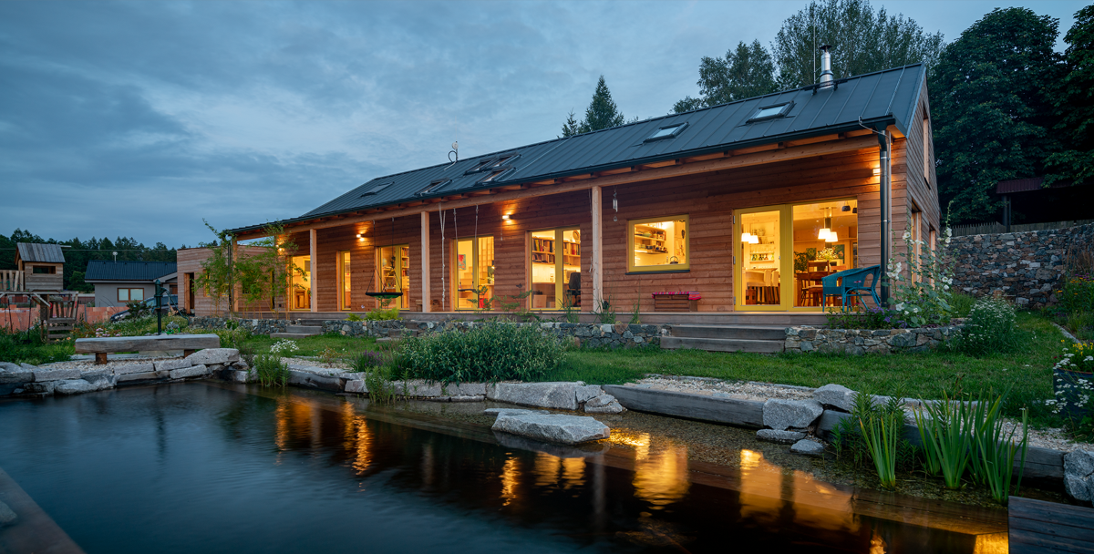 Dřevostavba inspirovaná japonskou architekturou s dřevěnou fasádou a jezírkem při západu slunce