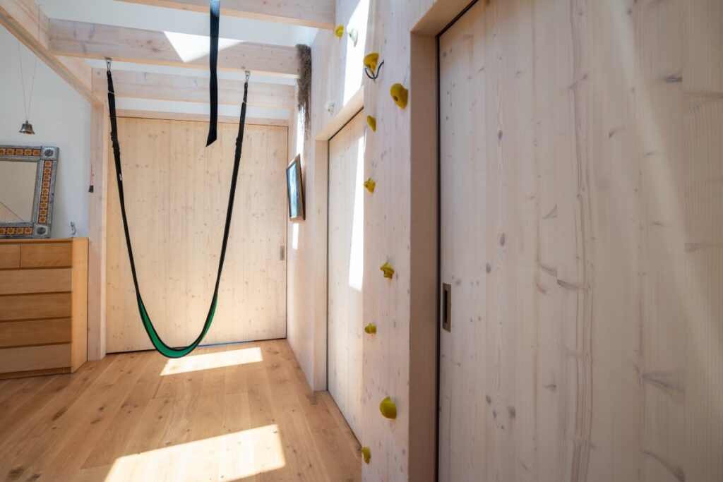 Chodba s dřevěným obkladem, lezeckou stěnou a houpací sítí