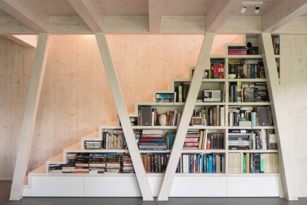 Vestavěná knihovna pod schody v interiéru s přiznaným dřevem