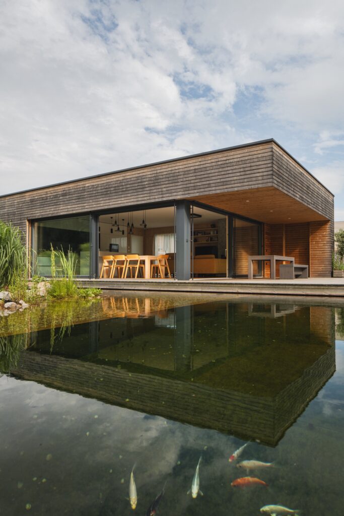 Dům s terasou a jezírkem s koi kapry před proskleným obytným prostorem