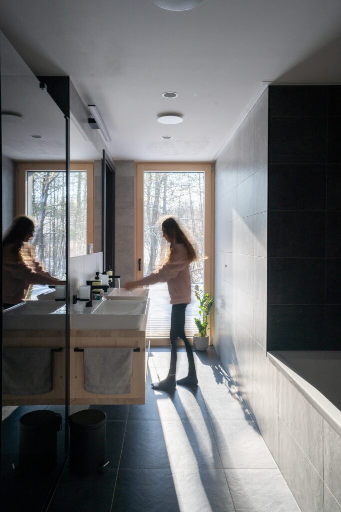 Koupelna ve vzorovém domě s dřevěnými prvky a velkými okny s výhledem