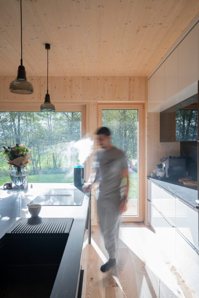 Kuchyně s dřevěnými stěnami a výhledem na zahradu