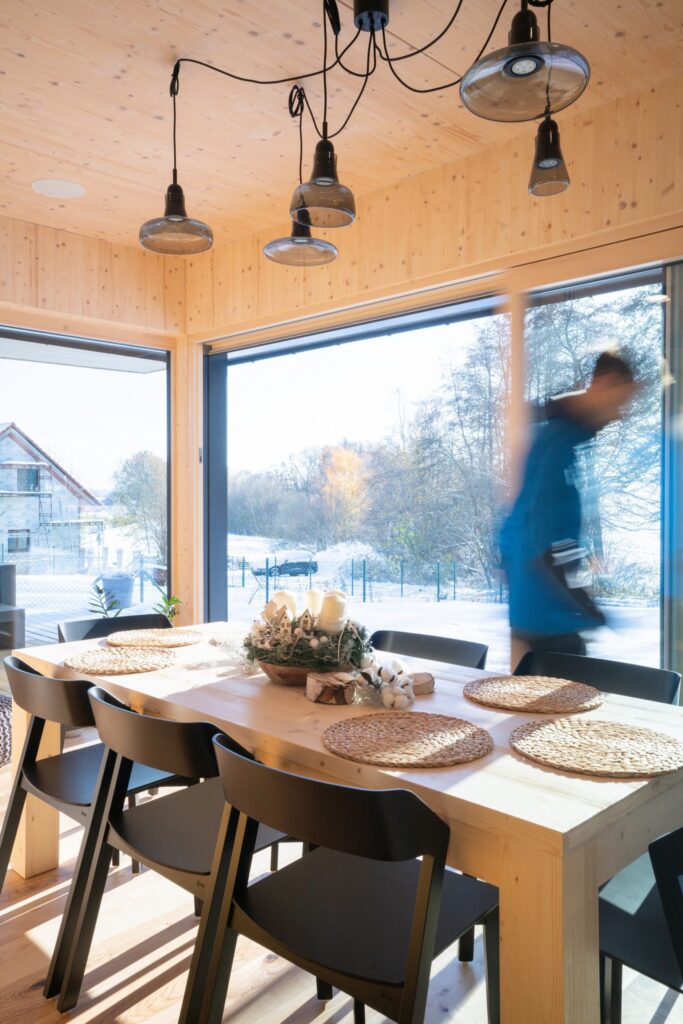 Jídelna ve vzorovém domě s velkými okny a výhledem na zasněženou krajinu