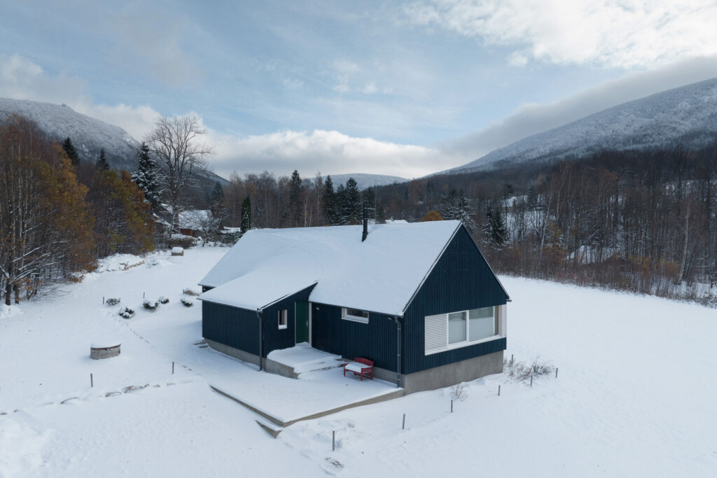 Modrá dřevostavba pod sněhem.