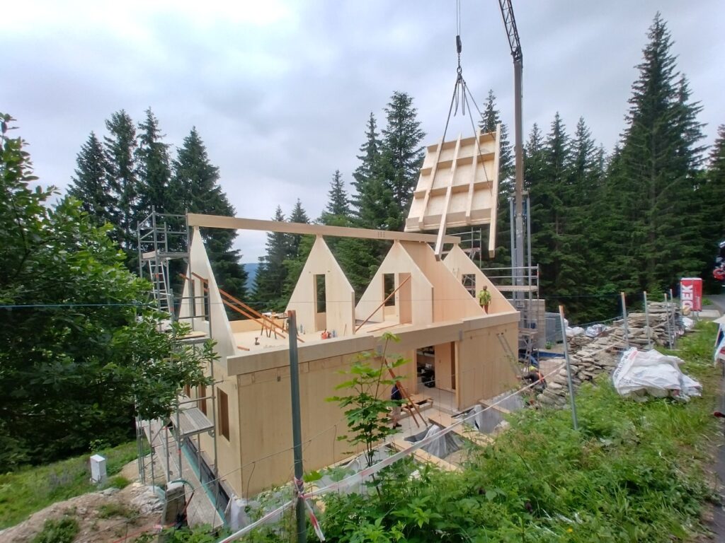 Montáž střešních panelů z CLT na hrubou stavbu dřevostavby v horách