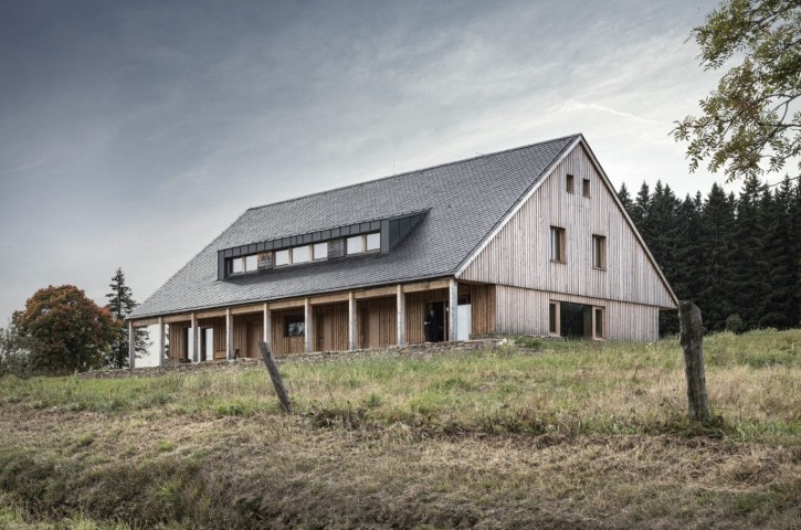 Dřevostavba se sedlovou střechou v horské krajině u lesa