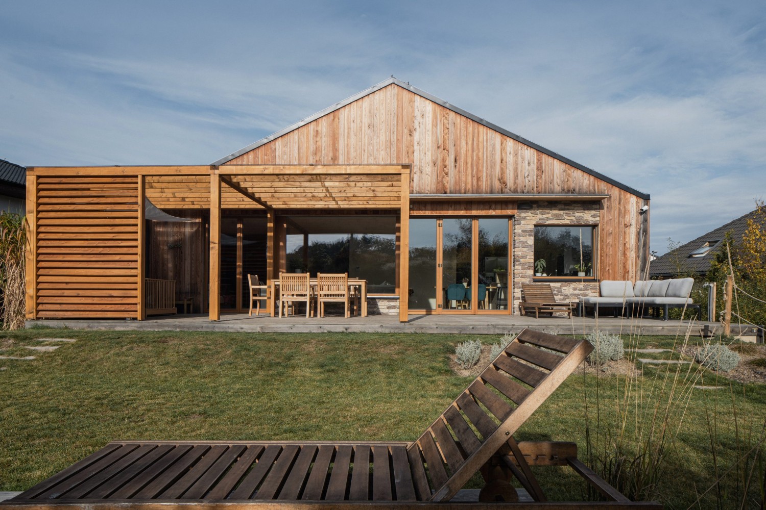 Přízemní dřevostavba s dřevěnou fasádou, terasou a lamelovým zastíněním