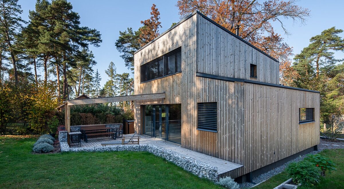 Rodinný dům s dřevěnou fasádou, pultovou střechou a venkovní terasou v zahradě - ilustrační foto k článku na téma cena domu.