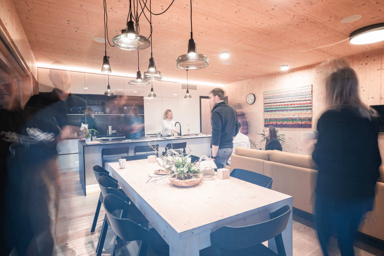 Interiér dřevostavby z CLT panelů s kuchyní, jídelním stolem a přiznaným dřevěným stropem.