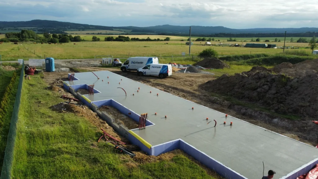 Dokončená betonová základová deska projektu Za lány s připravenými prostupy instalací a obvodovou tepelnou izolací.