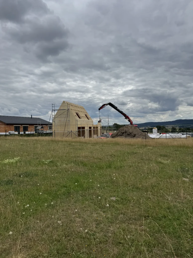 Rozestavěná moderní dřevostavba Za lány během montáže panelů NOVATOP v otevřené krajině na úpatí Brd.