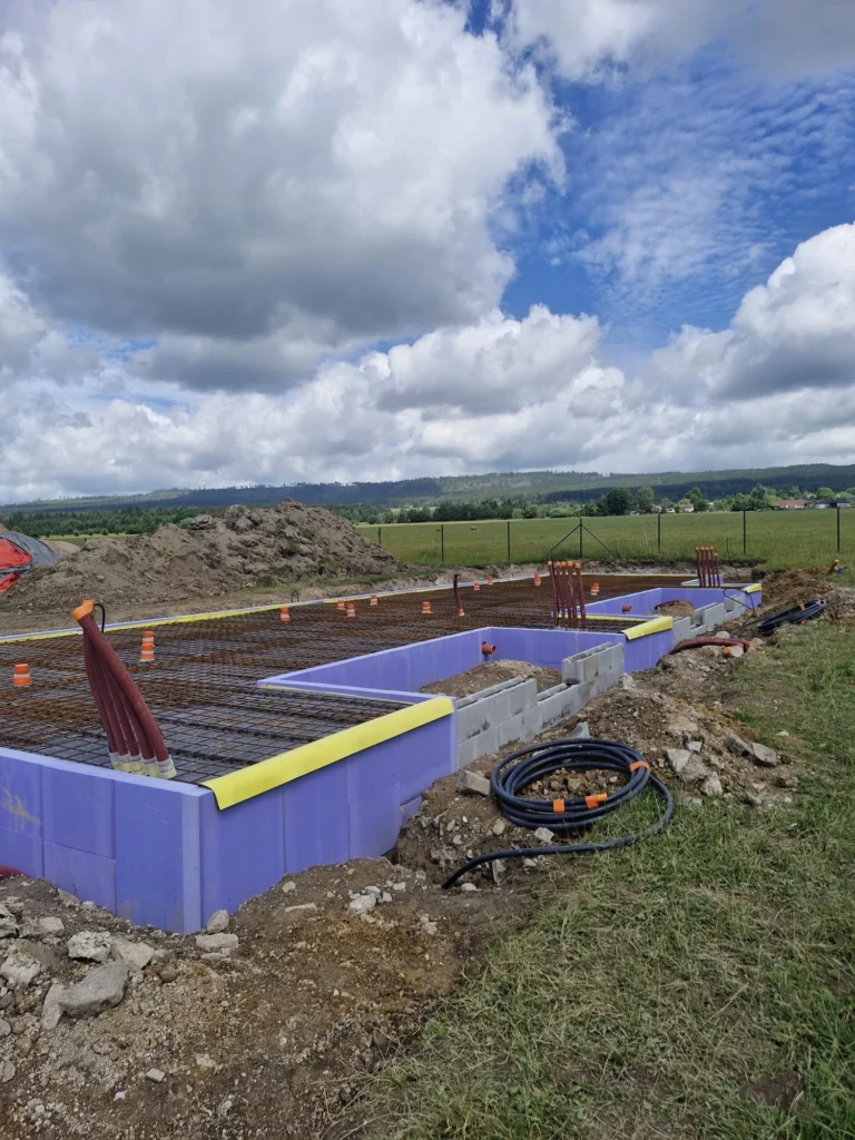 Příprava základové desky projektu Za lány s obvodovou tepelnou izolací, výztuží a prostupy instalací.