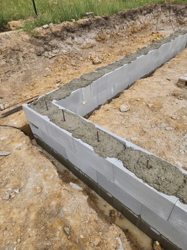 Detail vyzděných a vybetonovaných tvárnic ztraceného bednění s ocelovou výztuží pro základy stavby v Zalánech.